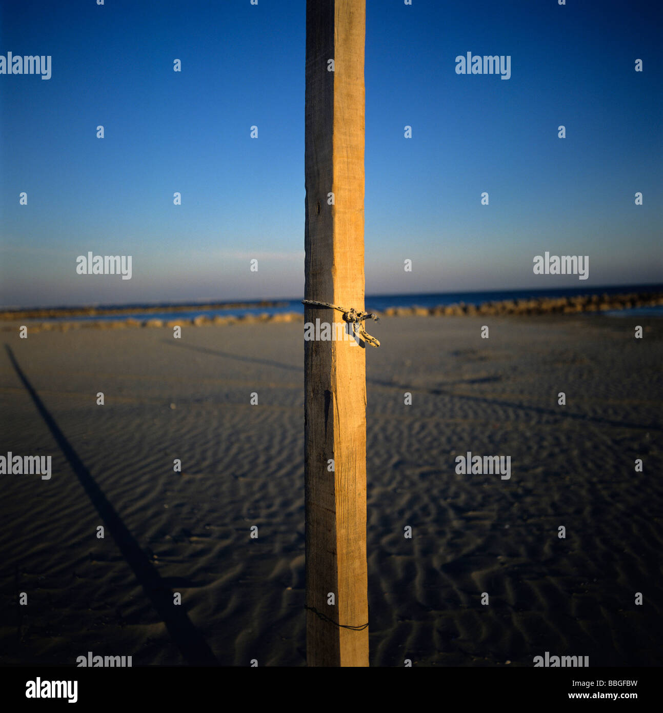 Isolated wooden post on the beach at sunset. France. Stock Photo