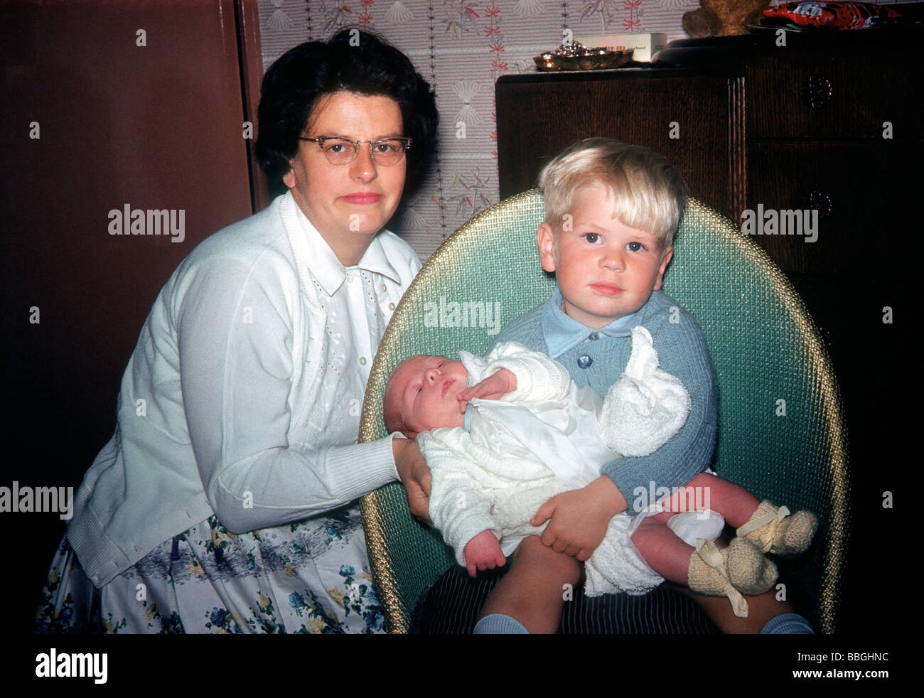 Proud Mum Betty Walton with her young son Colin, holding his new-born baby brother Malcolm in their lounge photographed by dad. Stock Photo