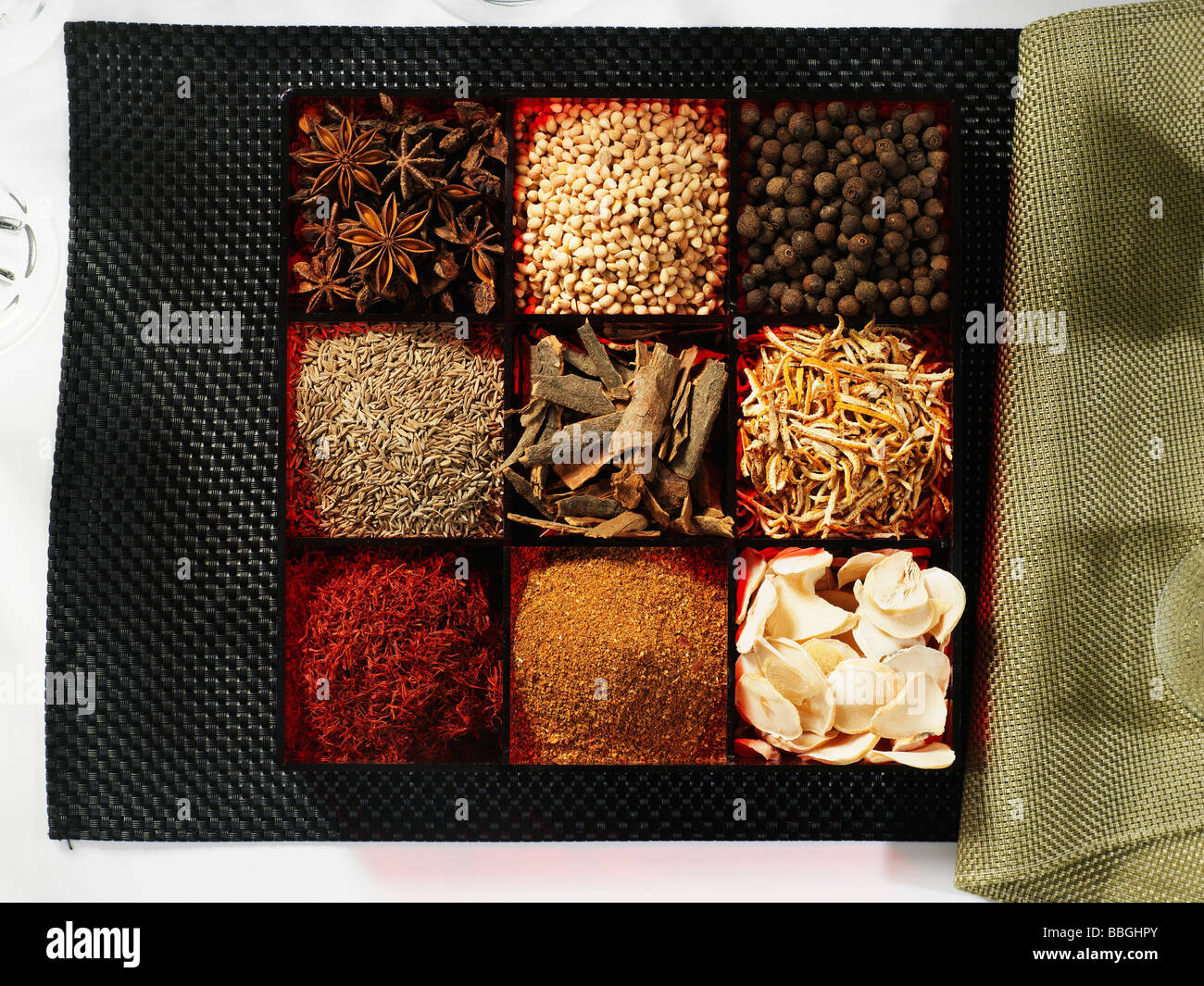 A selection of different spices in a spice box on a black background with a green napkin Stock Photo