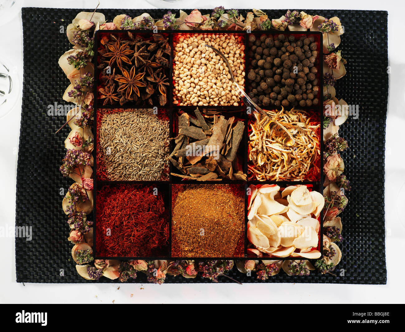 A selection of different spices in a spice box surrounded by dried flowers Stock Photo