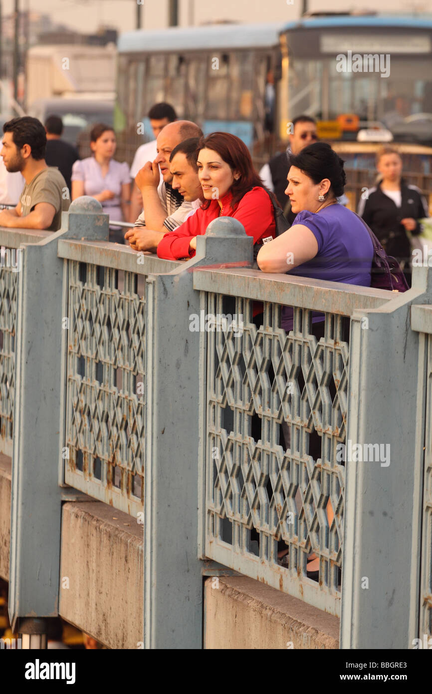 Istanbul Turkey local Turkish people women stand watching the evening sunset on the busy Galata Bridge Stock Photo