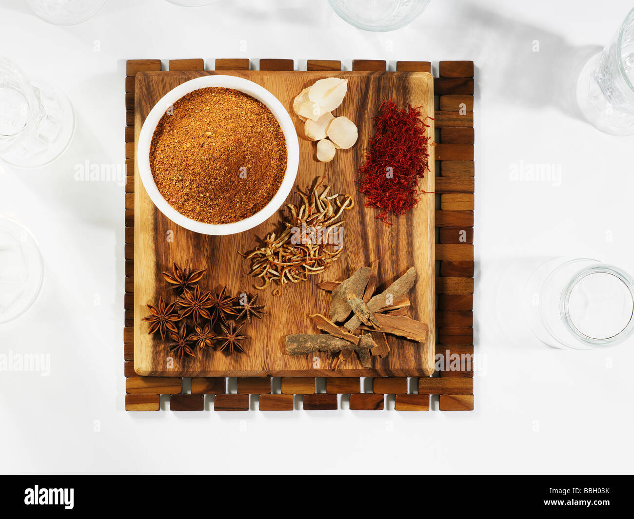 A selection of spices laid out on a wooden board on a wooden table setting Stock Photo