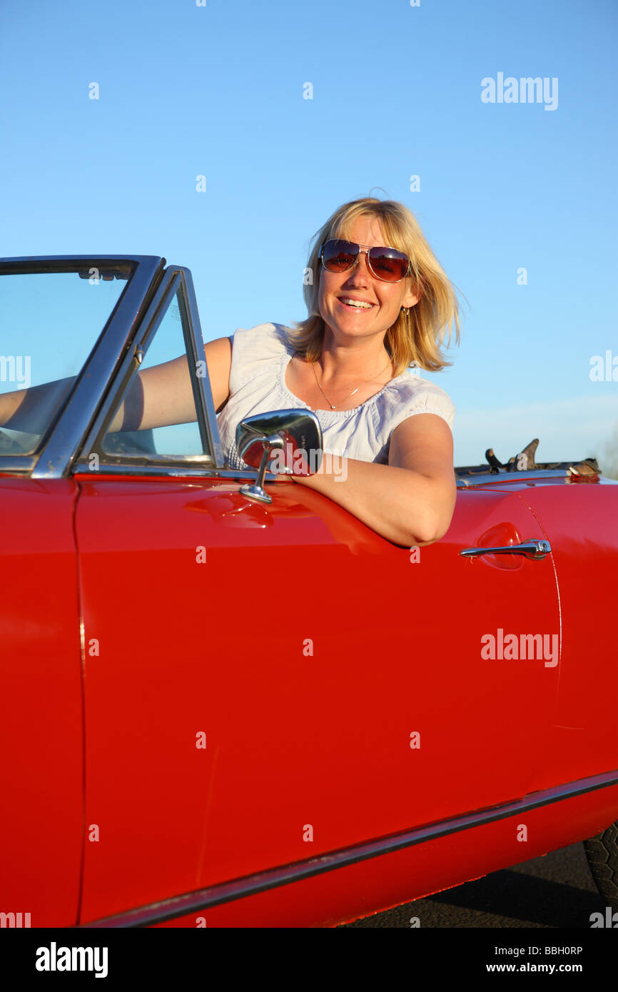 Young woman in red convertible car Stock Photo