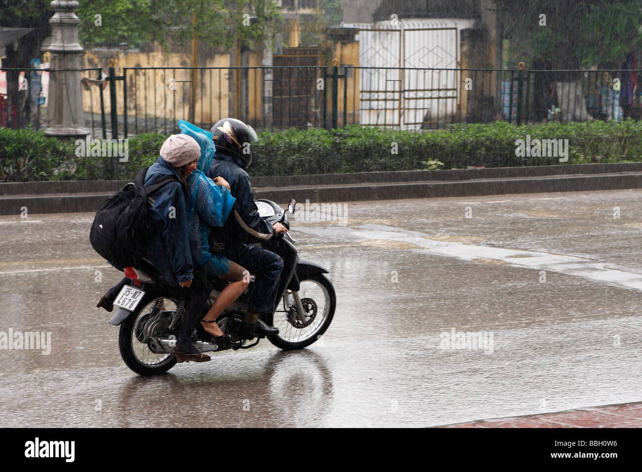3 people riding scooter on wet road in heavy rain, "Ninh ...