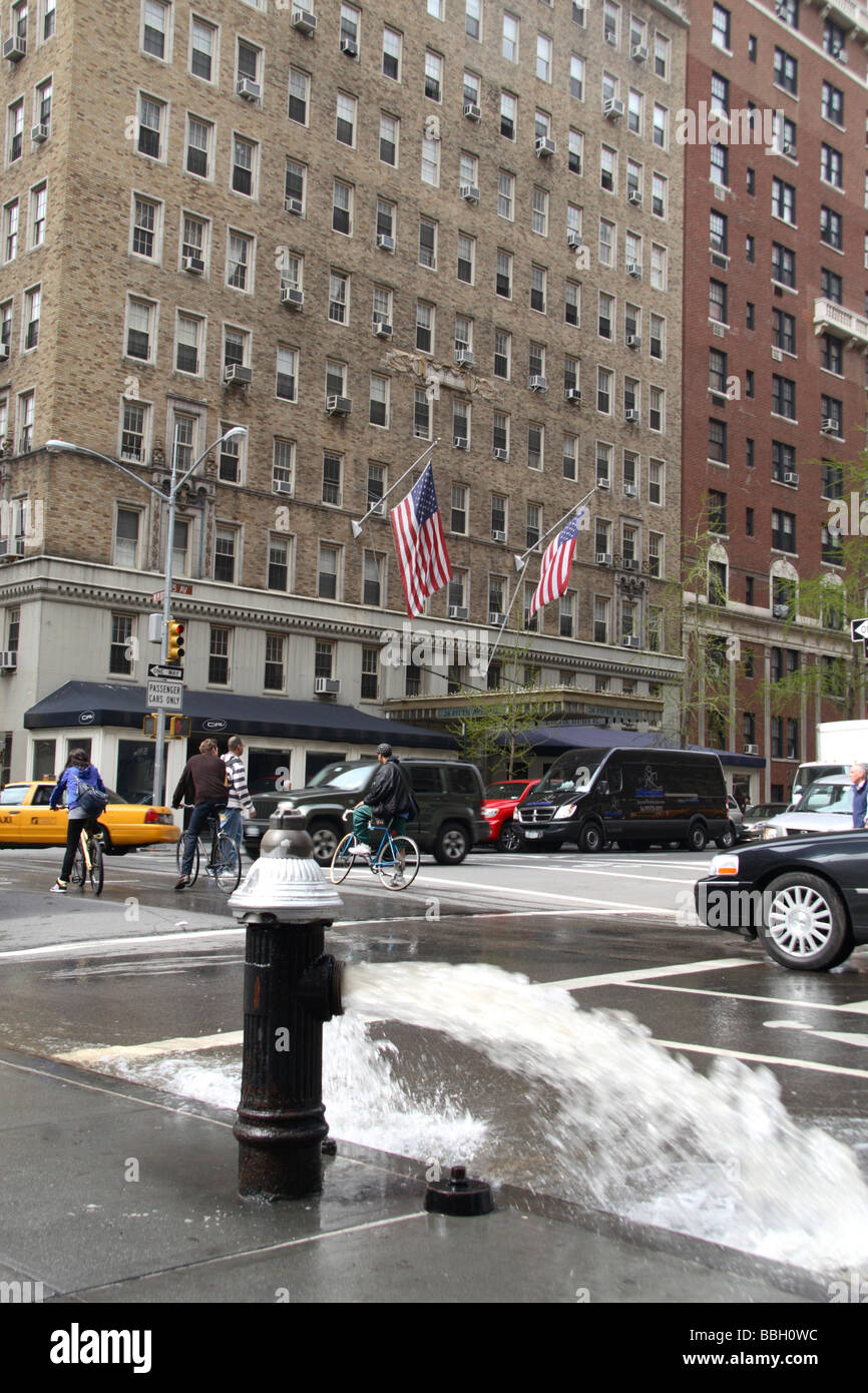 An open fire hydrant flooding the road on Fifth Avenue, New York Stock