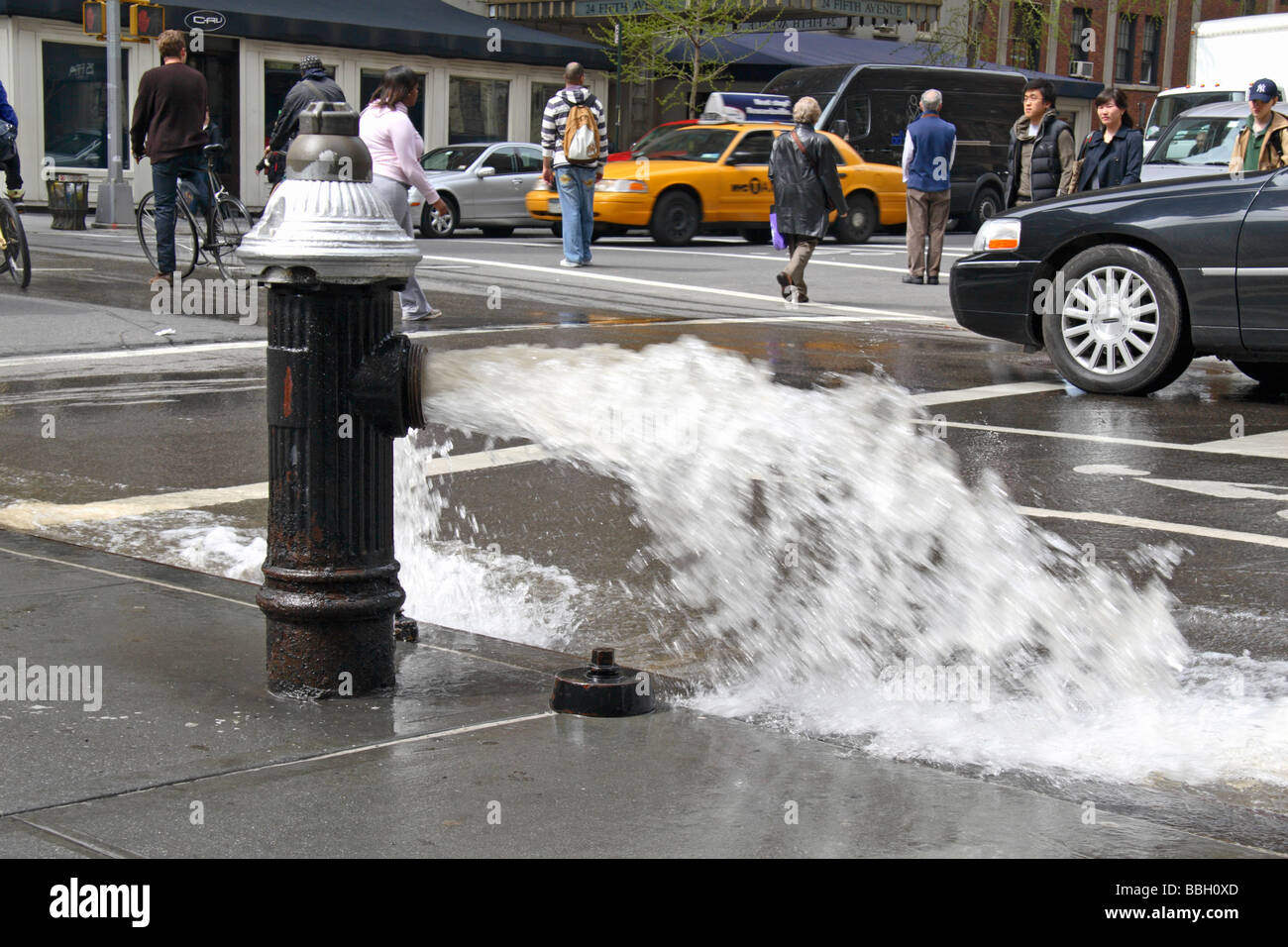 An open fire hydrant flooding the road on Fifth Avenue, New York Stock