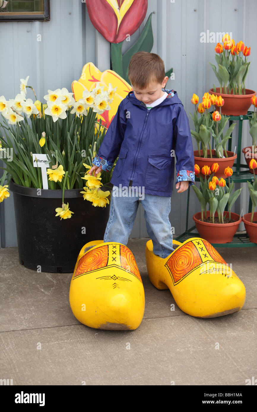 Young boy standing in oversized wooden shoes Stock Photo