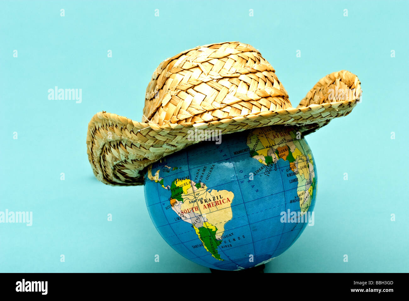 Straw hat on top of a small world globe Stock Photo