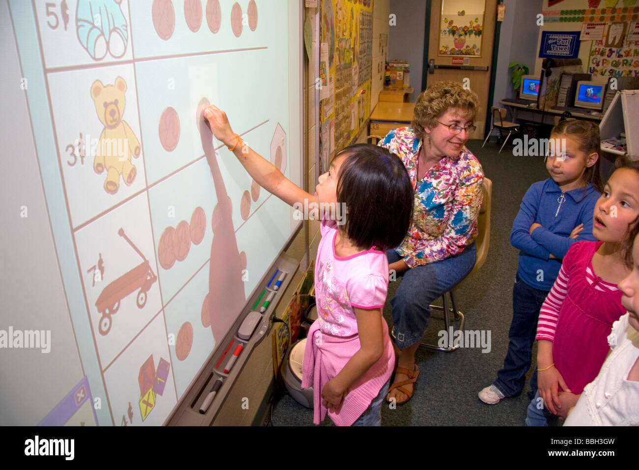 Kindergarten students use an interactive whiteboard in the classroom of
