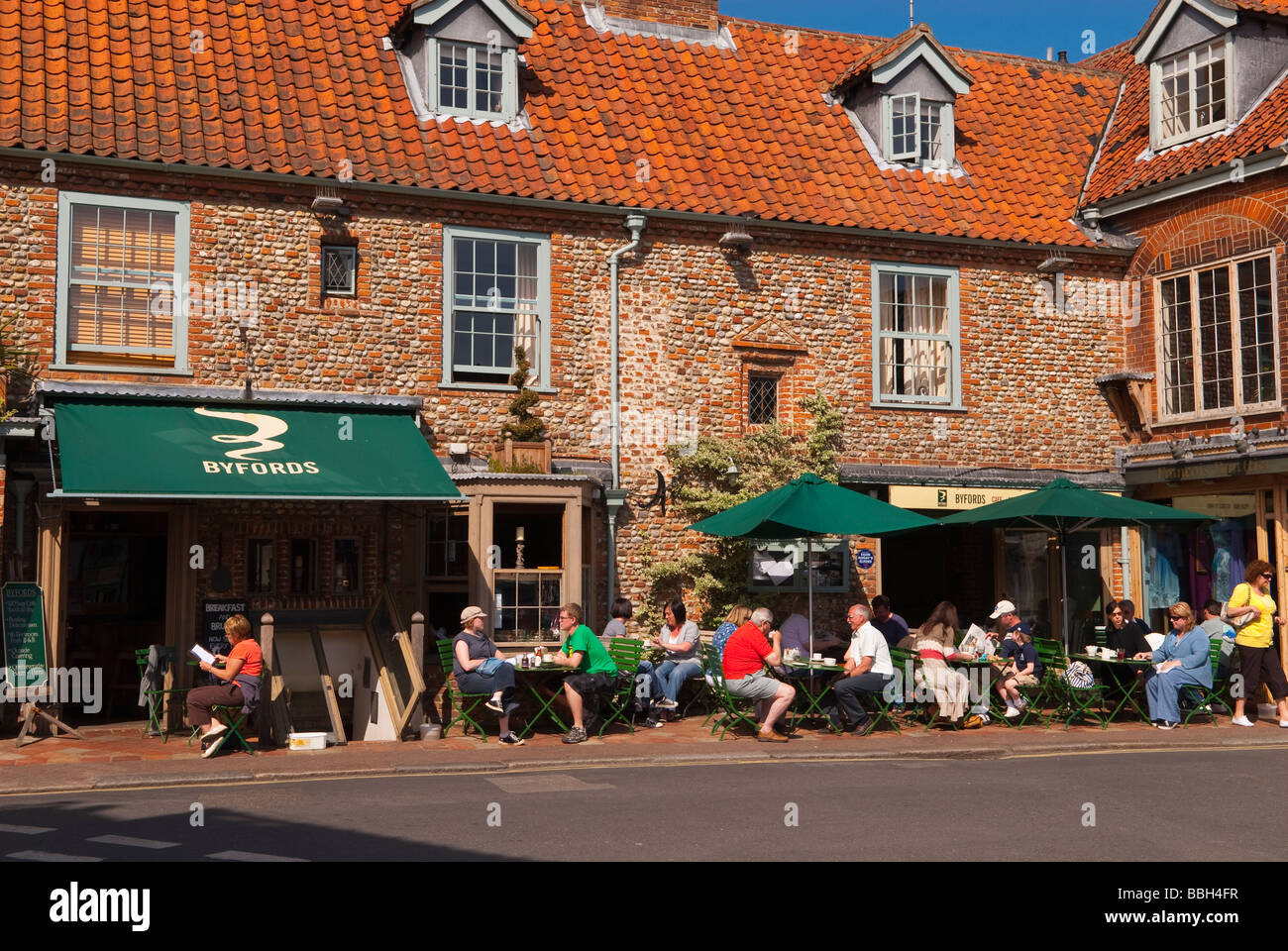 Customers sitting outside in the sun drinking tea and coffee at the Byfords delicatessen restaurant cafe in Holt Norfolk Uk Stock Photo