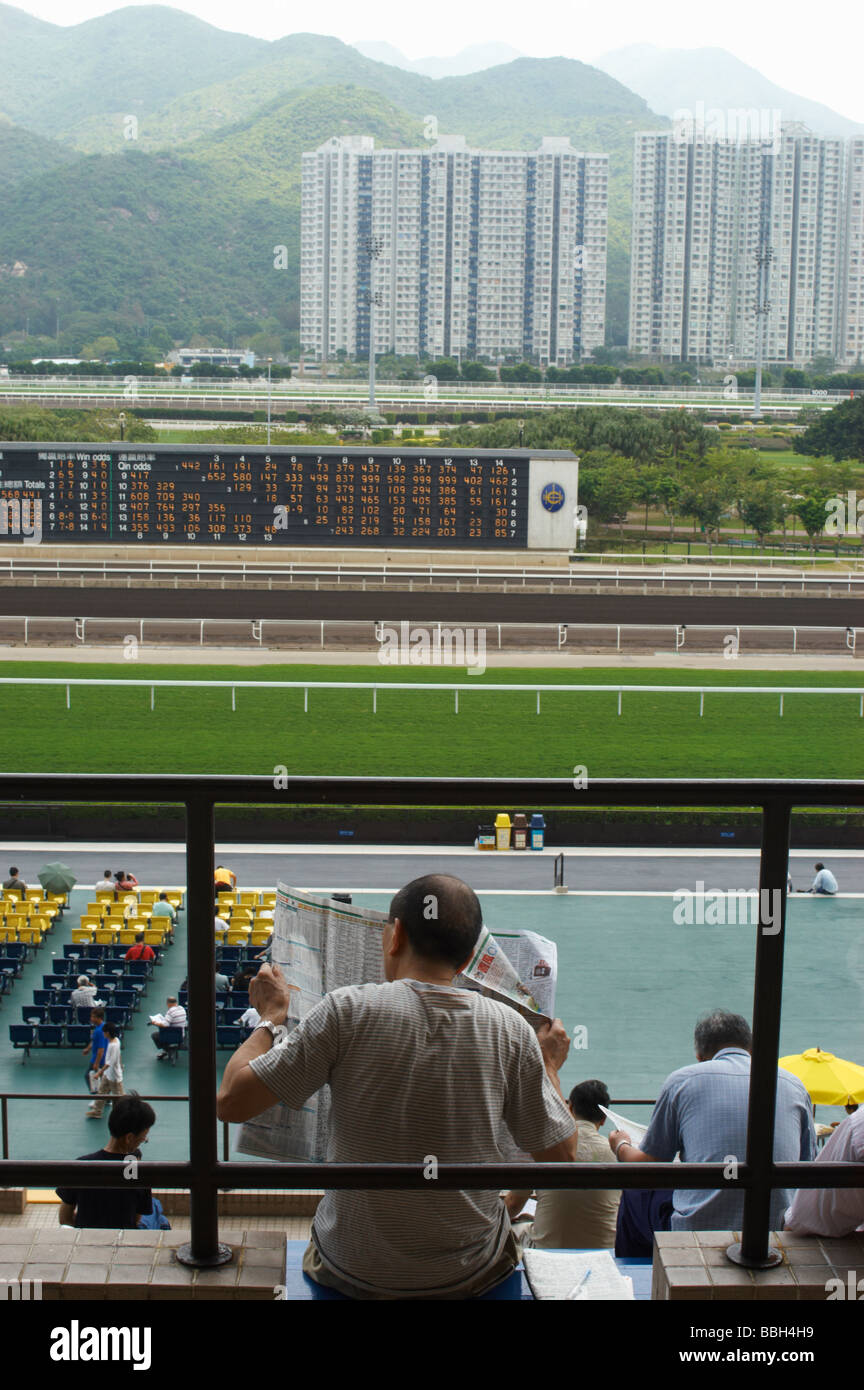 Chinese man reading the racing newspaper at Sha Tin Race Course Hong Kong Stock Photo