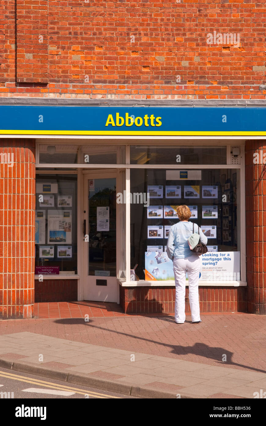 A woman looking in the window of the Abbotts estate agents window at