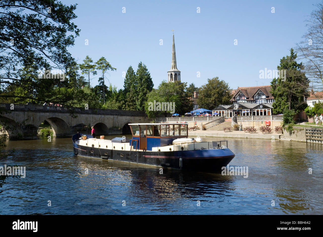 A barge heads downriver towards the bridge on the river Thames at Wallingford, Oxfordshire, UK Stock Photo