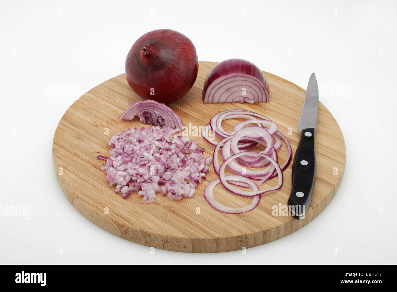 Red Onions (Allium cepa), peeled, diced onions, onion rings on a wooden board, with a knife Stock Photo