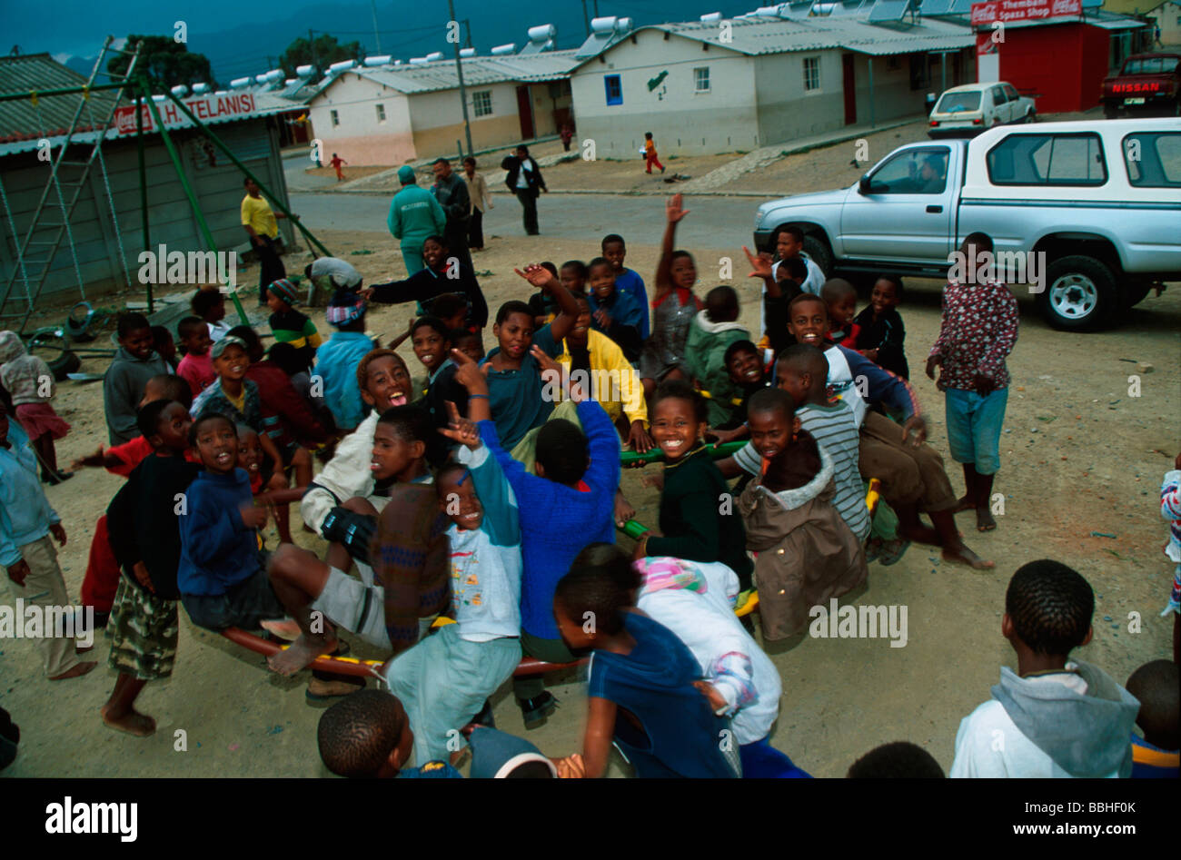 Children crowd onto a round a bout outside the Lwandle Migrant Labour Museum on a weekday afternoon Stock Photo