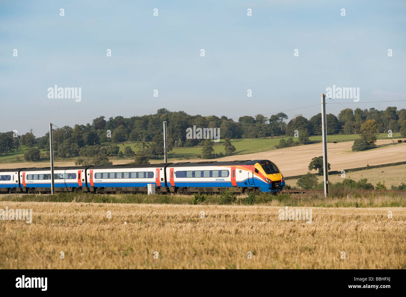 Passenger train in East Midlands Trains livery speeding through the English countryside on a sunny summers day Stock Photo