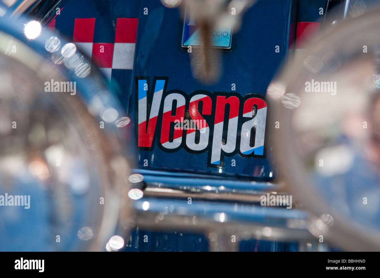 Red, white and blue Vespa logo behind chrome headlights Stock Photo