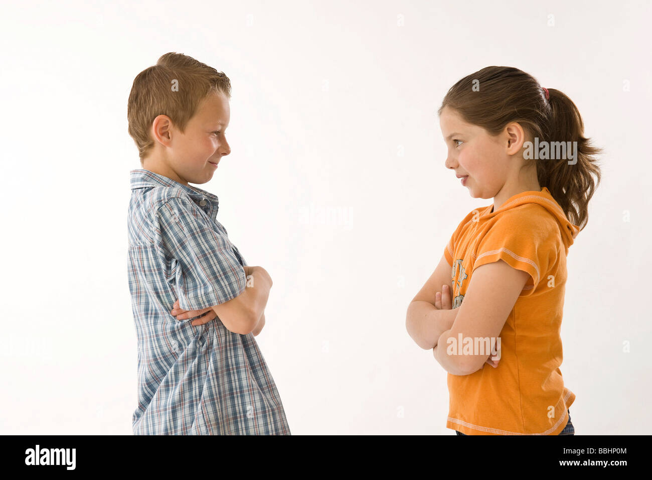 Boy and girl standing opposite each other with folded arms Stock Photo