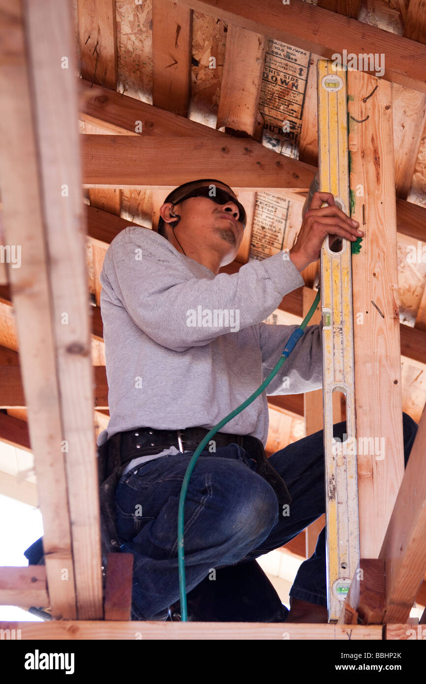 Carpenter using a level to see if a post is plumb on a construction job Stock Photo