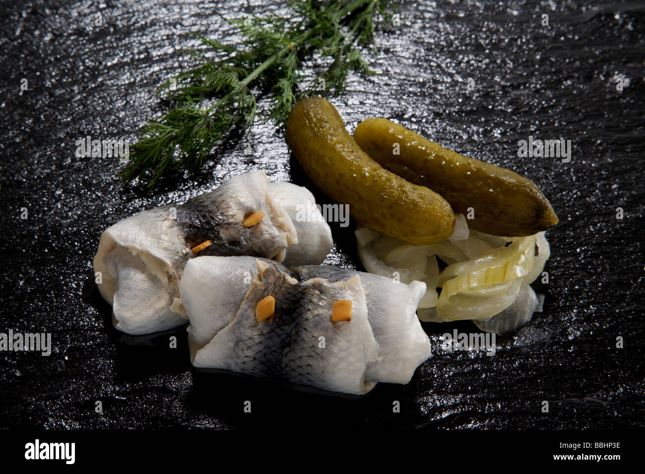 Pickled herring (Rollmops) with onions and gherkin on a slate Stock Photo Alamy