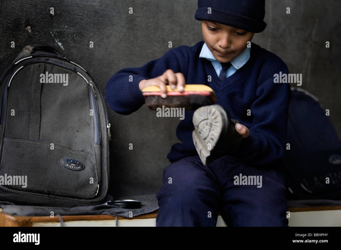 Boy at orphanage polishing his shoes hires stock photography and