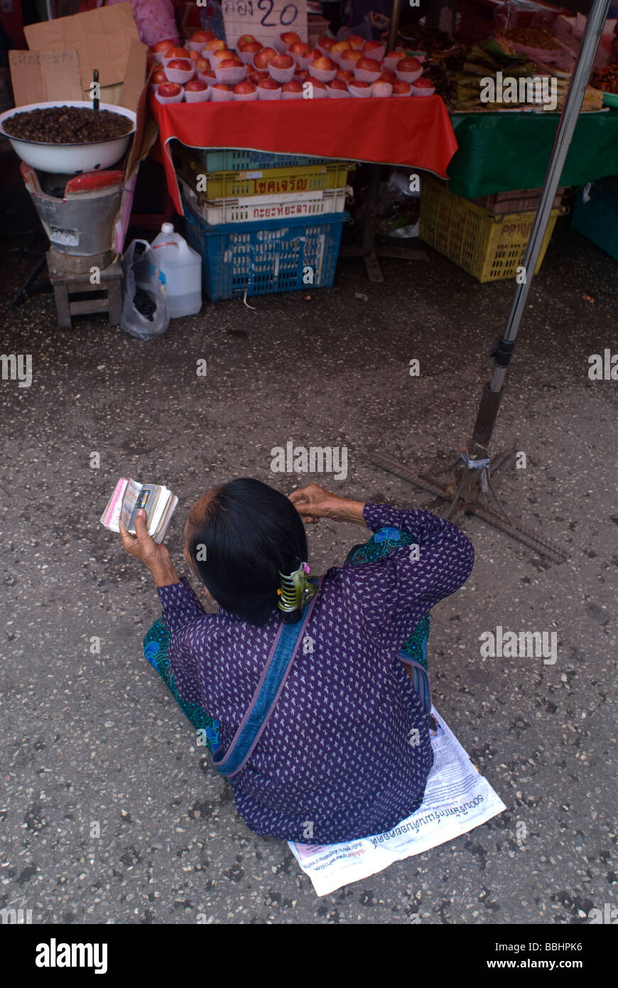 Old woman sitting on the ground at a market in Chiang Mai Thailand ...