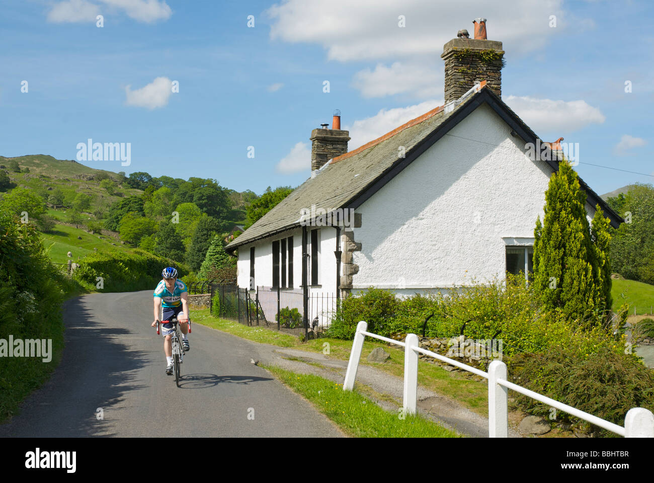 Cyclist passing through Troutbeck village, near Ambleside, Lake District National Park, Cumbria, England UK Stock Photo