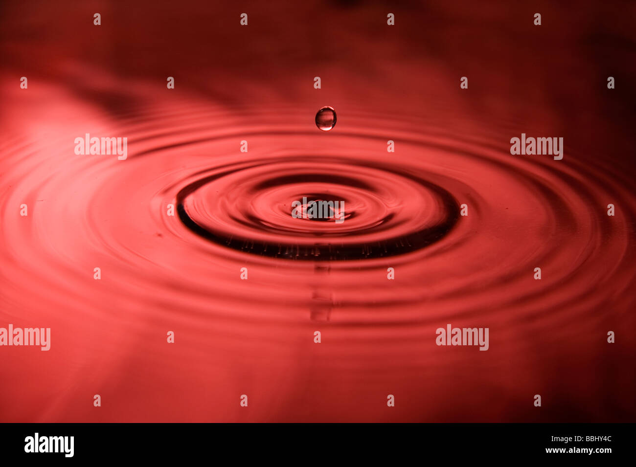 Single drop of water falling. The red sky reflects in the water Stock Photo