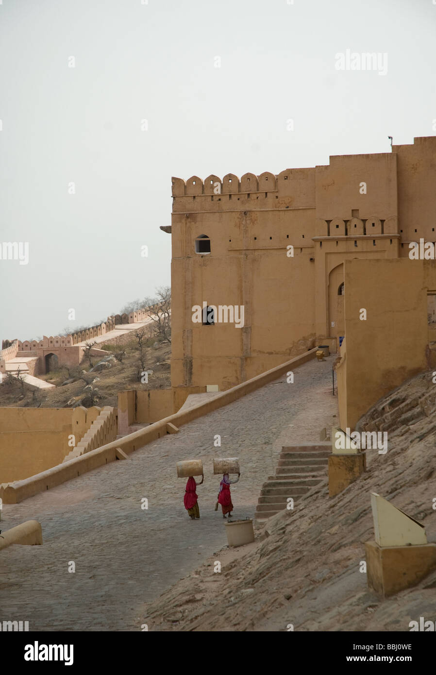 two Indian women carry oil drums along the steep path Stock Photo