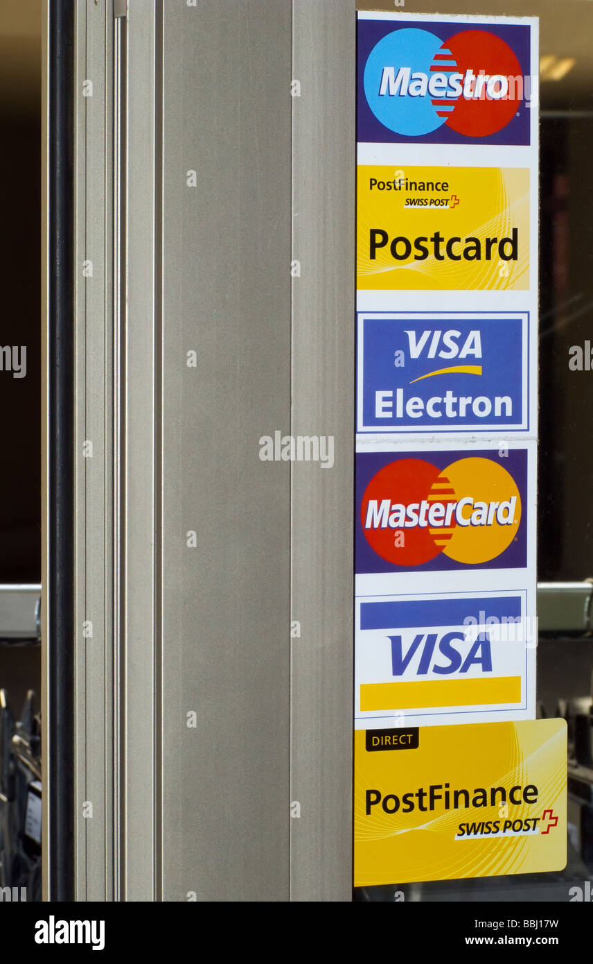 Logos of accepted credit cards are displayed at the entrance door to a store. Stock Photo