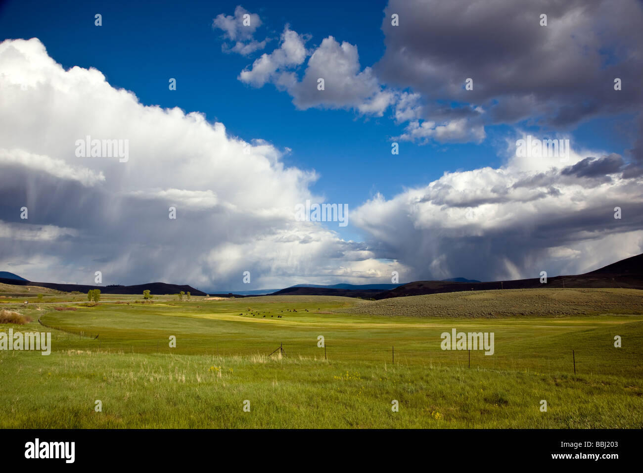 Springtime view southeast of ranchland towards the Sawatch Range of mountains and clearing stormy skies Colorado USA Stock Photo