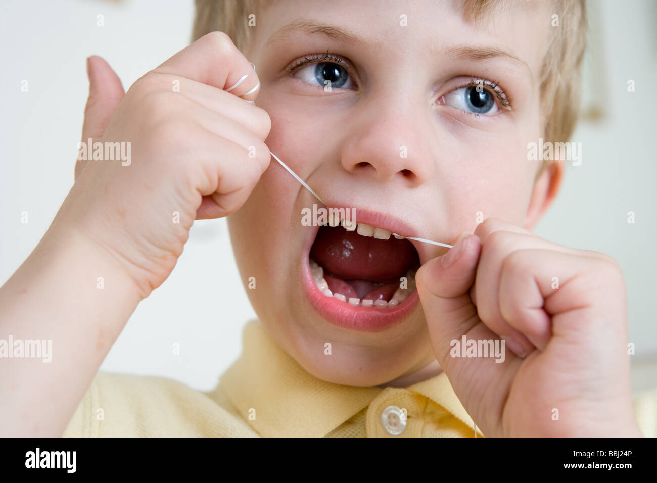 A small boy using Dental floss to care for teeth and gums Stock Photo