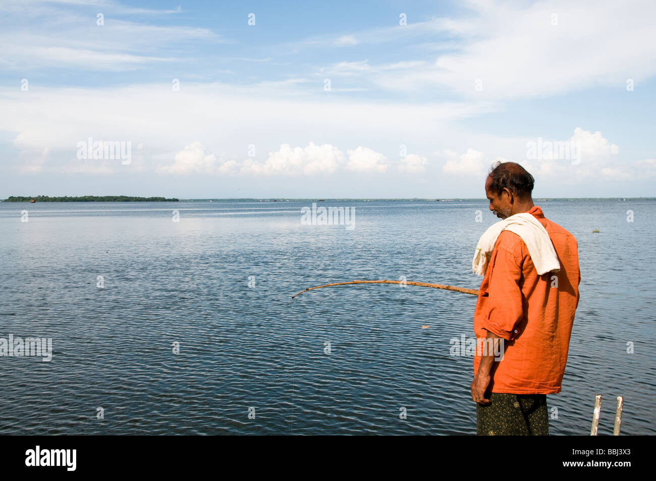 Indian fisherman fishing on dock in still water lake, backwaters kerala Stock Photo