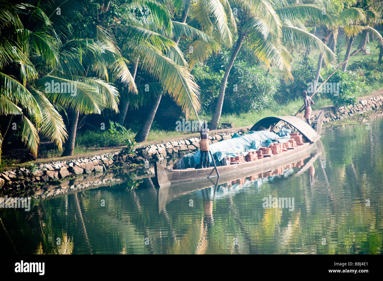 Man poles his boat laden with bricks along Kerala's backwaters Stock Photo
