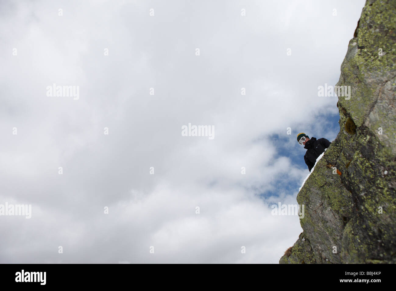 Snowboarder inspects the drop off a cliff which he will jump off, in the ski resort of Les Deux Alps, The Alps, France Stock Photo