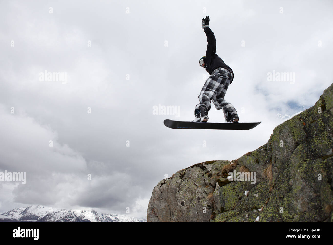 Snowboarder jumps off a cliff in the ski resort of Les Deux Alps, part of the Grande Galaxie Ski Area, The Alps, France Stock Photo