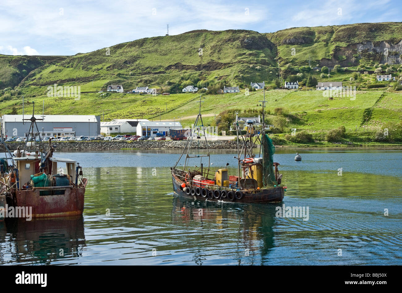 A fishing boat arrives at the Uig harbour in Skye Scotland on a sunny spring day Stock Photo