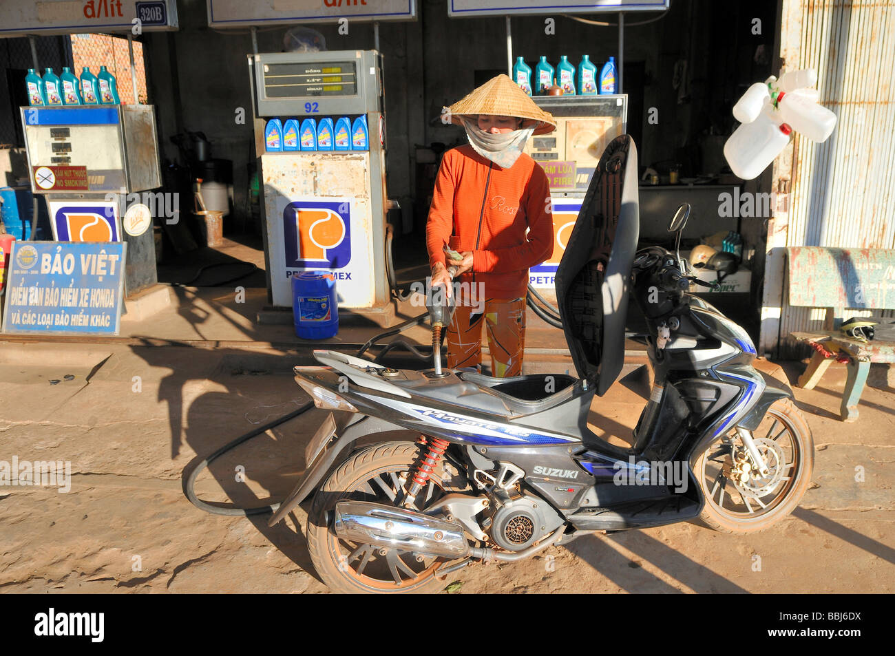 Gas station, woman wearing a reedhat refueling her scooter, Doung Dong