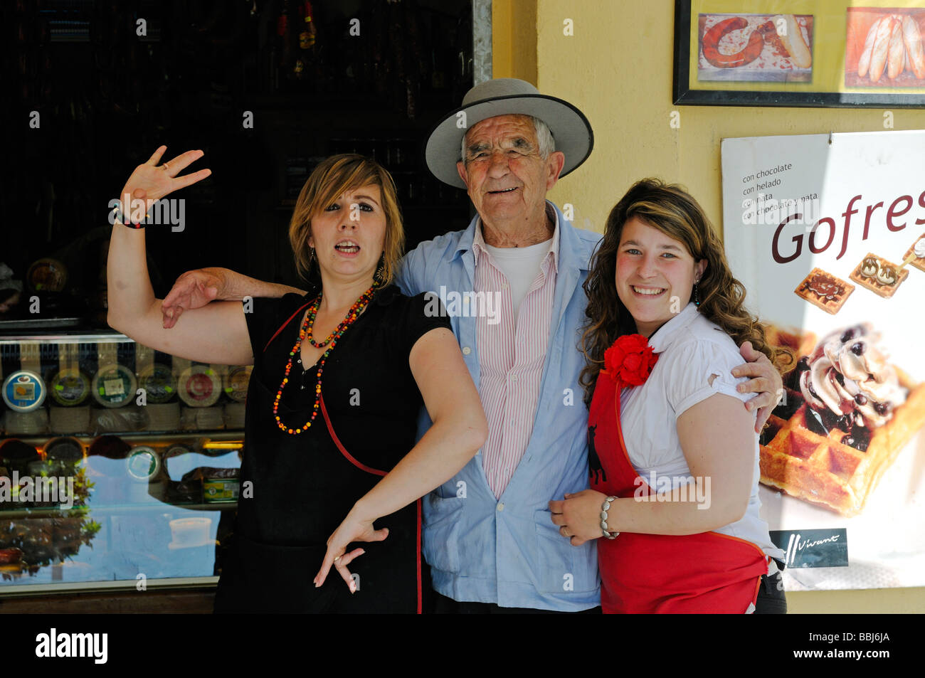 Informal portraits of two young Spanish women and older man in front of shop Spain Stock Photo
