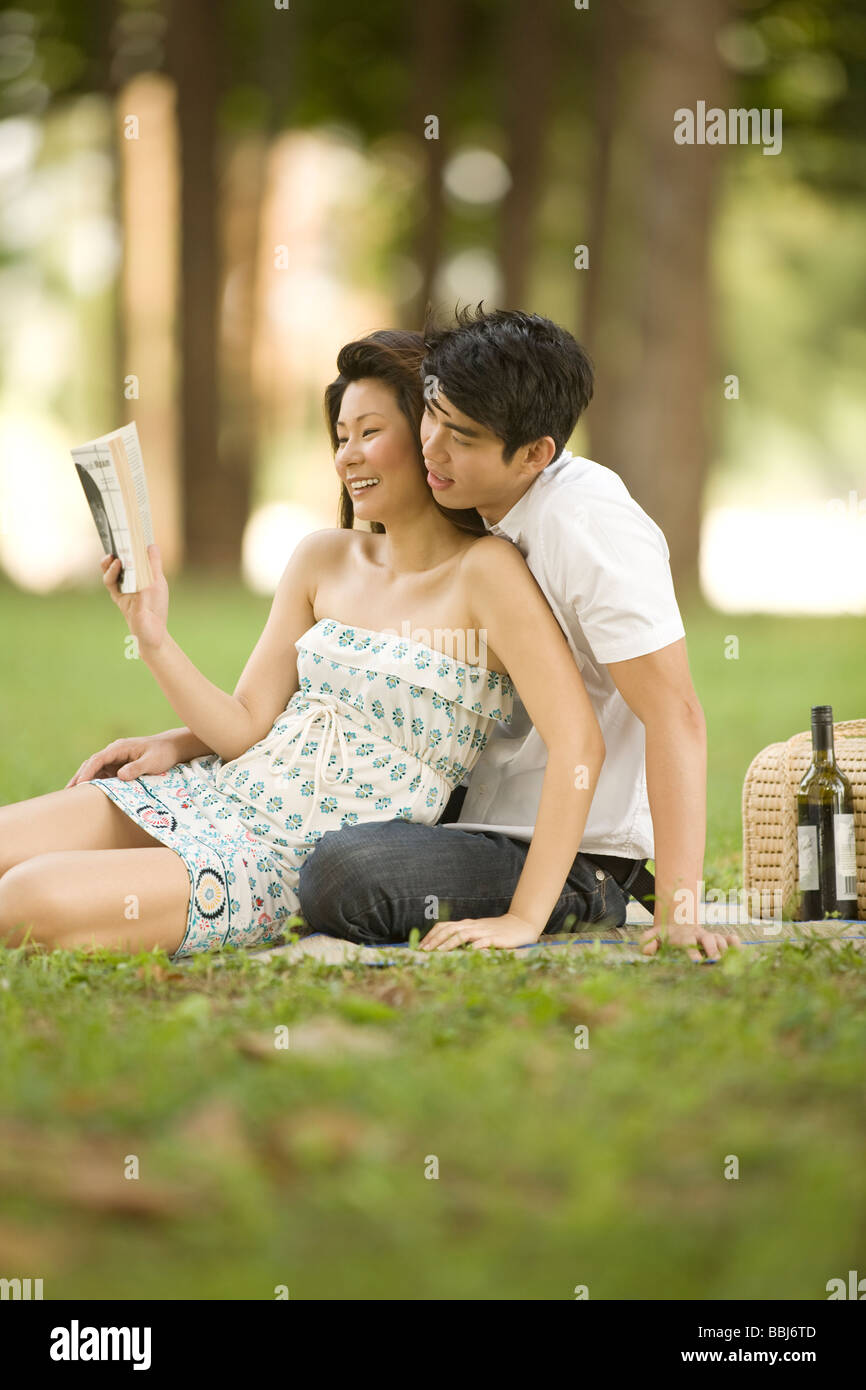 Young couple having picnic in the park, reading Stock Photo