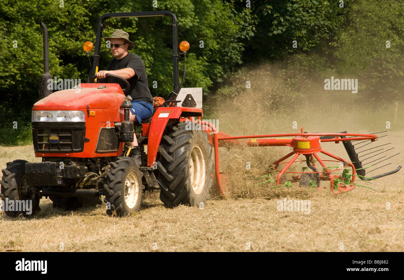 hay turning by tractor and farmer Stock Photo Alamy