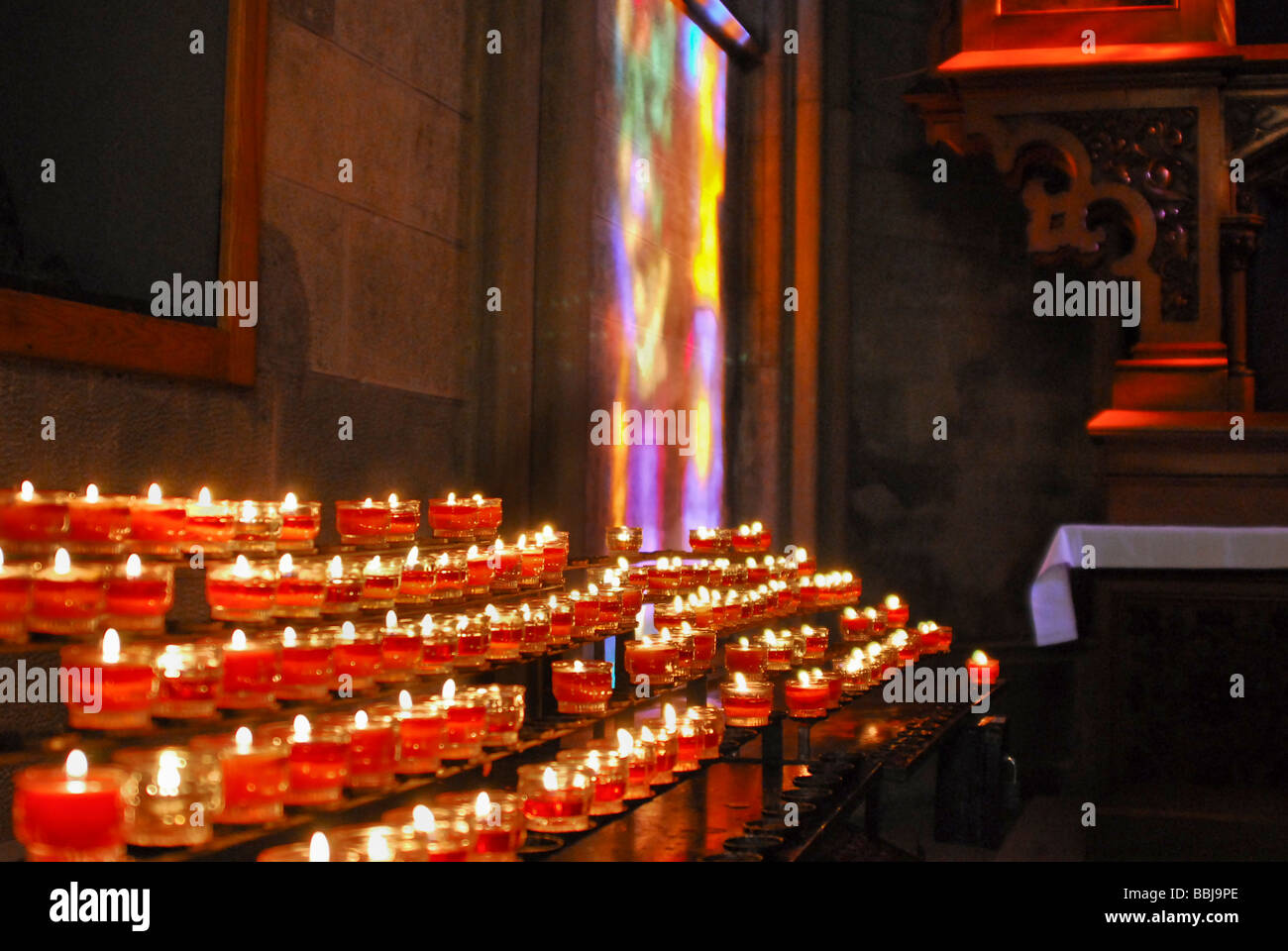 Candles in a catholic church in front a of a stained glass window light