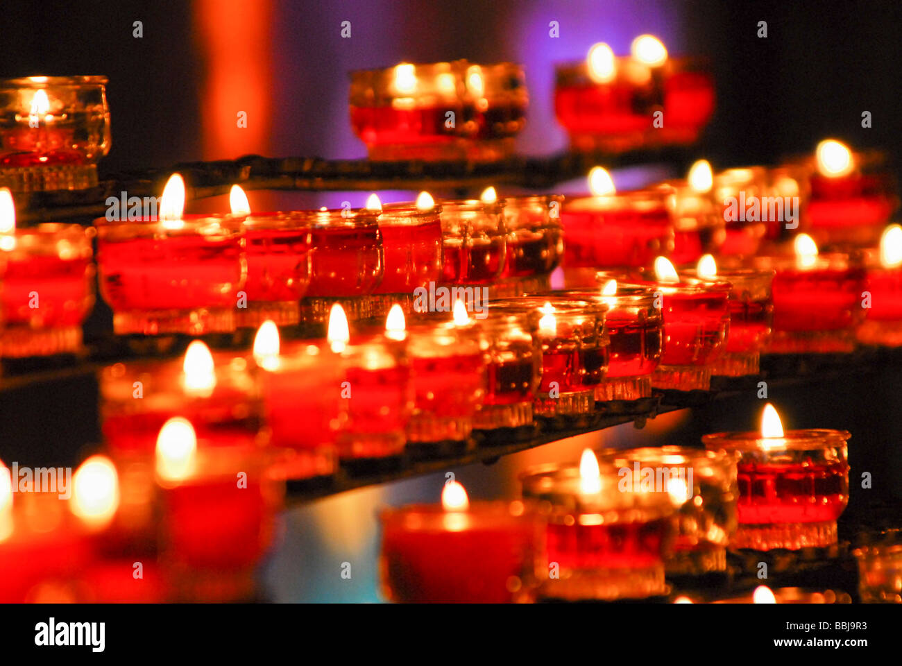 Candles in a catholic church in front a of a stained glass window light