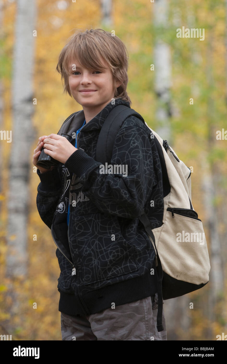 Smiling 10 year old boy with binoculars and hemp backpack, Lake Katherine, Riding Mountain National Park, Manitoba Stock Photo