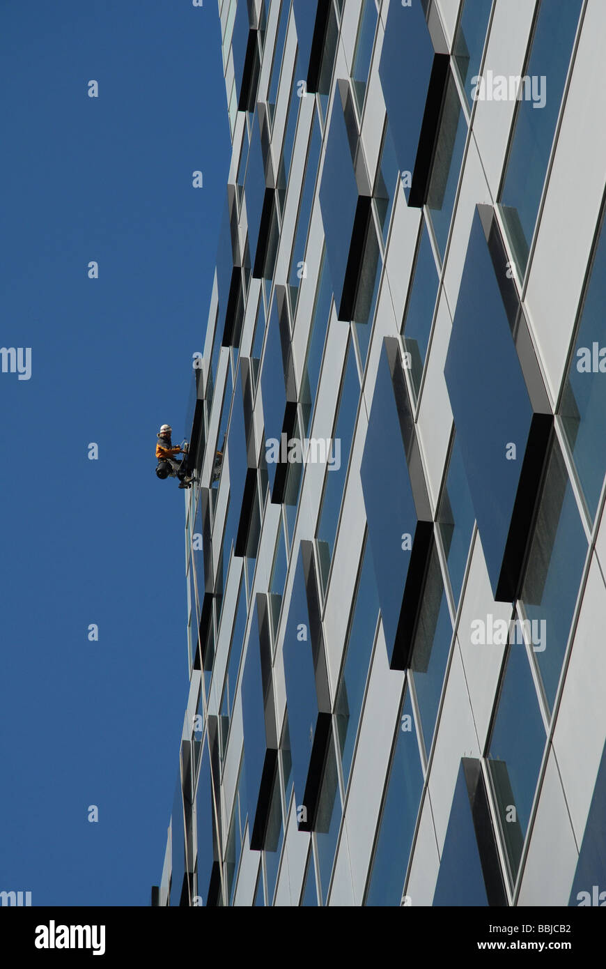 A window cleaner or washer works high up a tower block in the city Stock Photo