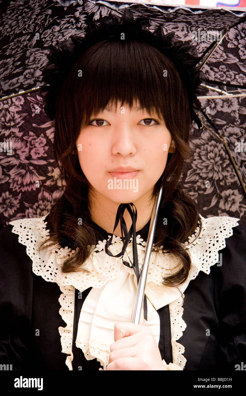 Tokyo, Harajuku. Cosplay. Close up portrait of young Japanese woman in Classic Gothic Lolita style clothing with umbrella, posing looking at viewer. Stock Photo