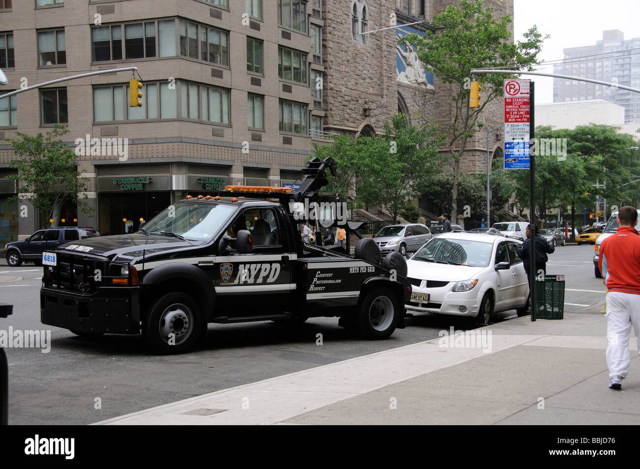 Parking violation NYPD tow away truck and female police officer attempting to gain entry into the car Manhattan New York USA Stock Photo