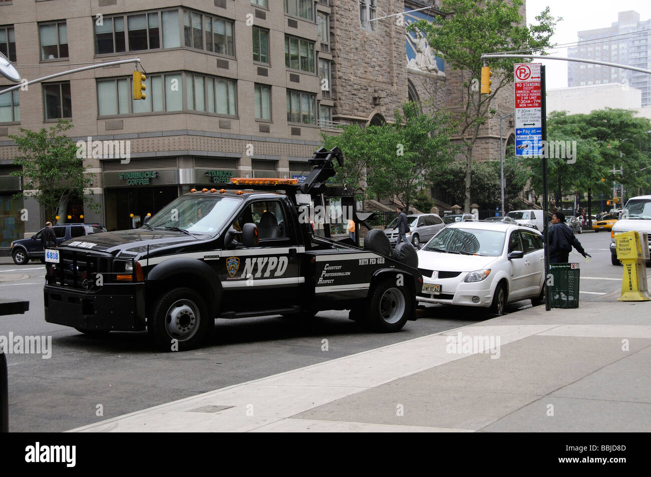 Parking violation NYPD tow away truck and female police officer attempting to gain entry into the car Manhattan New York USA Stock Photo