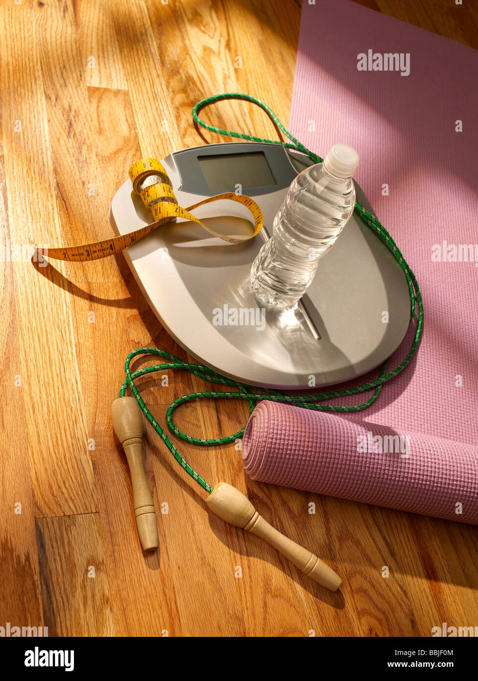 Scale on floor with yoga mat water and jump rope vertical Stock Photo