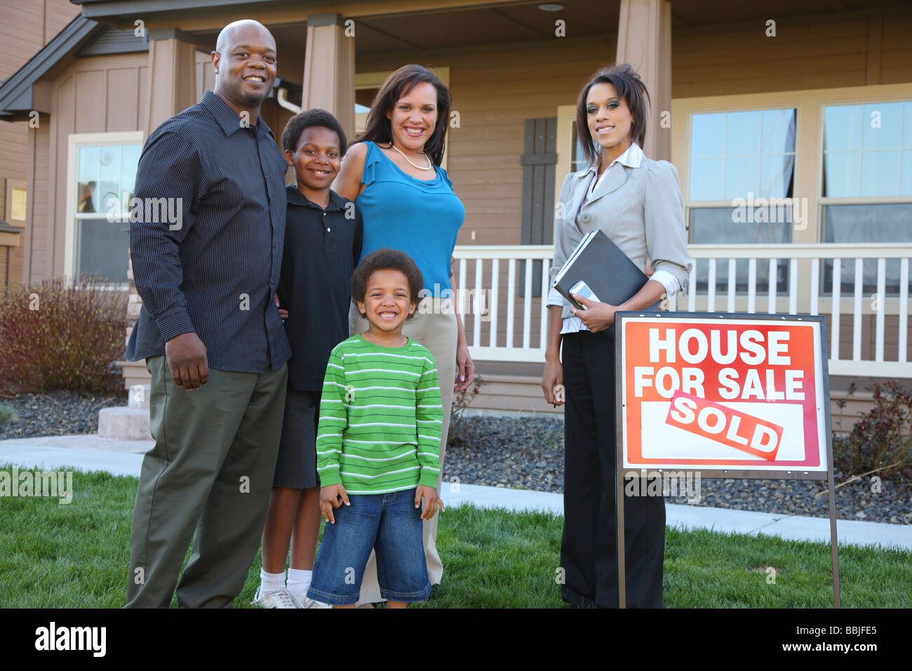 African American family and Realtor in front of new home Stock Photo
